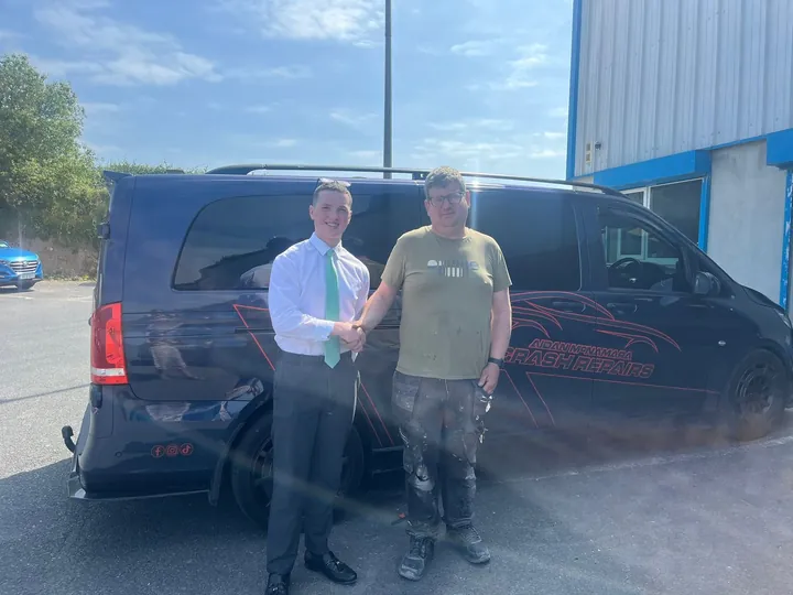 Dylan shaking hands with Aidan McNamara beside his van
